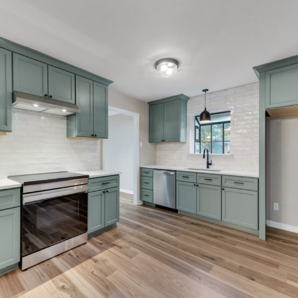 A redone kitchen that has teal cabinetry and beautiful countertops.<br />
