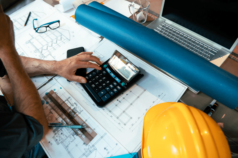 Architect calculating the costs of a kitchen or bathroom remodel at his work desk.<br />
