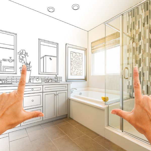 Hands framing a design of a bathroom remodel with completed cabinetry and countertops.<br />
