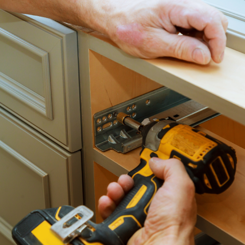 Close up of contractor installing kitchen cabinet railing for drawers.<br />
